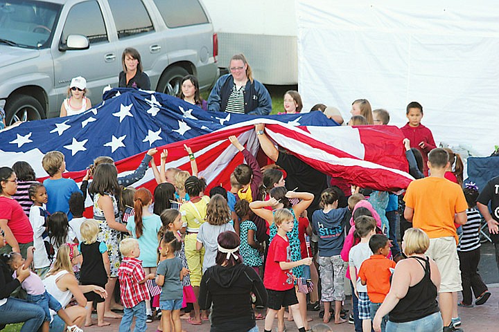 Dozens of children congregate to hold the American Flag out before the crowd put their right hands over their hearts for &quot;The Star-Spangled Banner&quot; at Moses Lake's Fourth of July celebration yesterday in McCosh Park.