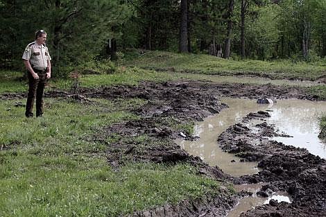 Jason Shueh/Valley Press Sanders County Deputy Chris McGuigan looks out over a mud pit at Jones Bench in Plains where &#147;mud boggers&#148; caused more than $16,000 in damages. The Sanders County Police Department and Forest Service are looking to prosecute mud boggers and will fence off land from the public where it has been abused.