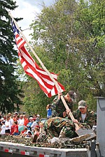 Members of Polson Boy Scout Troop 1947, Cash Sisler and Cody Basler hold the flag as Dylan McCrumb kneels to reenact the raising of the American flag on Iwo Jima.