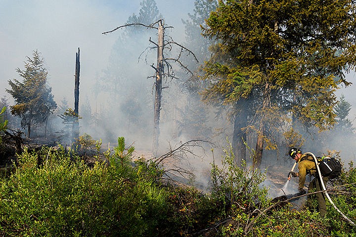 &lt;p&gt;A firefighter with the Idaho Department of Lands hoses down the perimeter of a brush fire as several acres smolder in Spirit Lake.&lt;/p&gt;