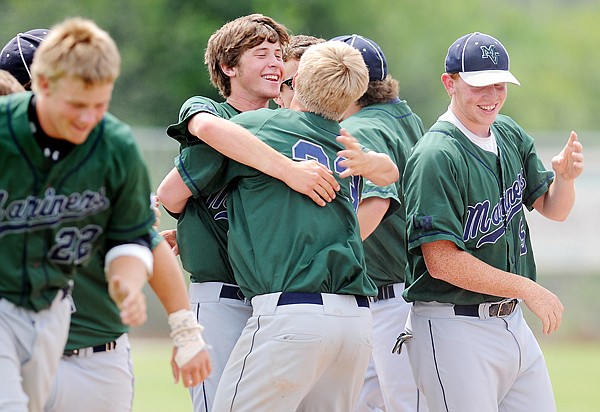 Mission Valley pitcher Justin Evertz, 16, center, gets a hug from Derrick Rathe, 33, as the team celebrates their win over Anacortes on Saturday afternoon at the John R. Harp Tournament in Kalispell.