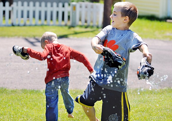 Sam Lovering, 8, right, and his brother Zachary, 6, fill their shoes with water and play in the sun and heat on Wednesday in Columbia Falls.