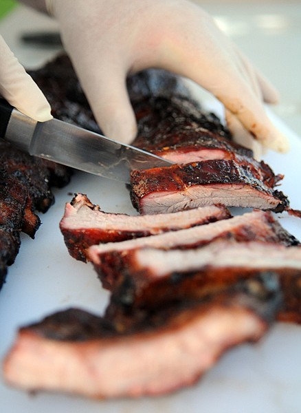 Greg Dulin slices up a rack of ribs to share with friends on Friday night in Kalispell.