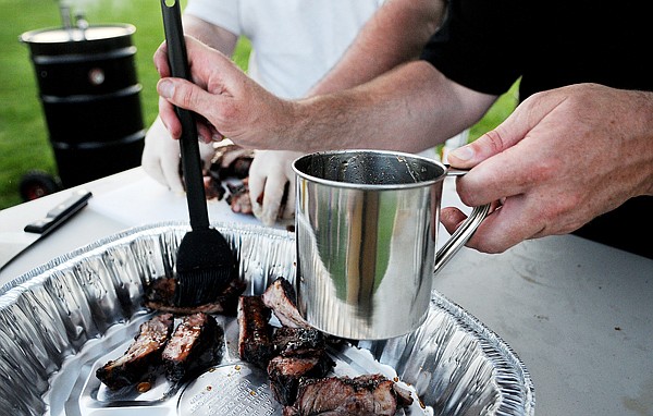 David Gassaway adds an extra bit of sauce before serving up the first rack of ribs on Friday night in Kalispell.