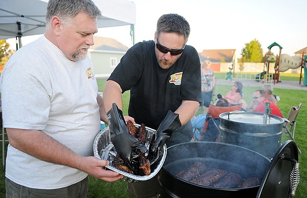 Greg Dulin, left, and David Gassaway pull ribs out of the smoker on Friday night in Kalispell. The &quot;Smokin' Hot Grill Friends&quot; took home the grand champion award at the Inland Northwest BBQ Idaho State Championship.