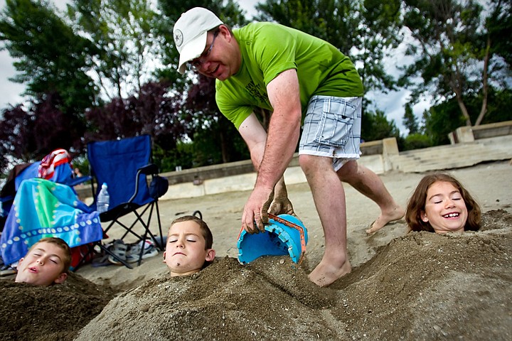 &lt;p&gt;JEROME A. POLLOS/Press Paul Twigg finishes covering his children, Jason Twigg, 11, from left, Aiden Twigg, 6, and Emma Twigg, 9, with sand Monday on the City Beach in Coeur d'Alene. The beach burial of the Twigg children has become a vacation tradition for the family on holiday from Calgary.&lt;/p&gt;