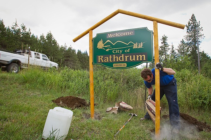 &lt;p&gt;Mike Dan, lead installer with Sign Service, pours a bag of concrete mix into a post hole Tuesday as he installs a sign at an entry point on Highway 41, one of three new signs.&lt;/p&gt;