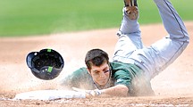 Mission Valley's Xavier Morigeau sends dust and his helmet flying as he slides into third base during the game against Anacortes on Saturday in Kalispell.