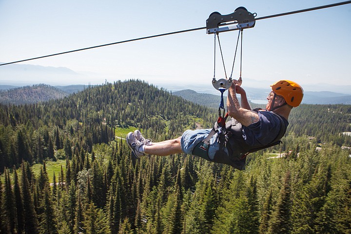 <p>Kelly Carberry of Stevensville takes in views of the Flathead Valley and Bad Rock Canyon as he rides down the new 1,900-foot zip line at Whitefish Mountain Resort on Wednesday morning. Wednesday, July 11, 2012 in Whitefish, Montana.</p>