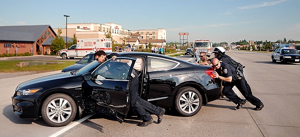 &lt;p&gt;Doug Overman, Stan Ottosen, and Mark Mulcahy, of the Kalispell Police Department and Rob Cherot of the Kalispell Fire Department work to move a vehicle involved in a two car accident on Tuesday, July 10, near the Hilton Garden Inn Conference Center in Kalispell.&lt;/p&gt;