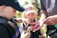 Ben and Brianna Stone fill the cache container with additional treasures before returning it to the hollowed-out stump where it will wait for the next geocachers to find.