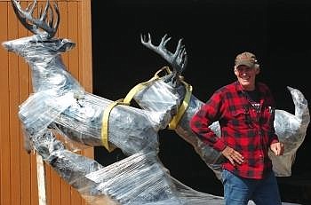 Gary Collier, owner of Kalispell Neon, smiles while standing next to the statue of two deer. Collier donated his time and truck to getting the Sherry Sander statue out of storage.