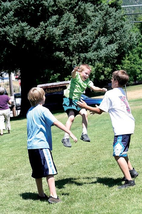 Nick Ianniello/Mineral Independent Brothers Tucker, left, and Billy Smith throw Clay Donnally into the air during the Lunch on the Lot beside Mullan Trial Bank in Superior Friday afternoon. Kids and adults teamed up to raise money for Relay for Life and the American Cancer Society.