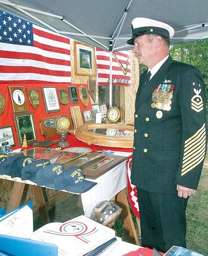 Canda Harbaugh/The Western News Herbert Gregory looks over artifacts and honors from his 36-year career in the U.S. Navy during his retirement party Saturday at his Troy home.