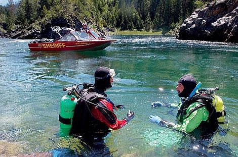 Chris Jordan/Daily Inter Lake&lt;br&gt;Chuck Curry, right, and Joe Billow, divers from the Flathead dive team, discuss a strategy Monday for searching a tricky eddy near the Devil's Elbow section of Flathead River. In the background is sheriff's deputy and diver Jordan White, who said the water is fast and tricky in the area where a swimmer went missing Sunday evening.