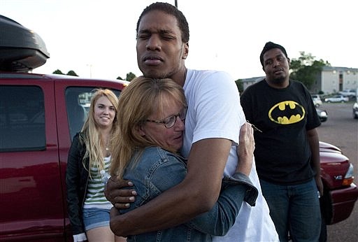 &lt;p&gt;Judy Goos, center left, hugs her daughter's friend, Isaiah Bow, 20, while eyewitnesses Emma Goos, 19, left, and Terrell Wallin, 20, right, gather outside Gateway High School where witnesses were brought for questioning Friday, July 20, 2012, in Aurora, Colo. A gunman wearing a gas mask set off an unknown gas and fired into a crowded movie theater at a midnight opening of the Batman movie &quot;The Dark Knight Rises,&quot; killing at least 12 people and injuring at least 50 others, authorities said. (AP Photo/Barry Gutierrez)&lt;/p&gt;