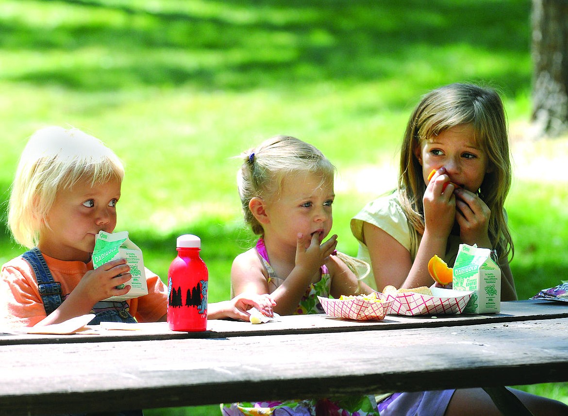 <p>Serena Carlson, form left, Finley Putzler, and Ali Putzler enjoy lunch from the Kalispell schools' summer meals program. (Aaric Bryan/Daily Inter Lake)</p>