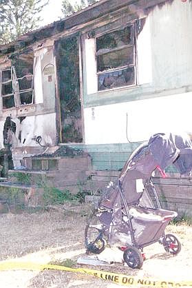 Canda Harbaugh/The Western News A stroller sits in front of the burned mobile home of Lorna Coffman. The 26-year-old woman and her 2-year-old son died in an early-morning fire on Saturday.