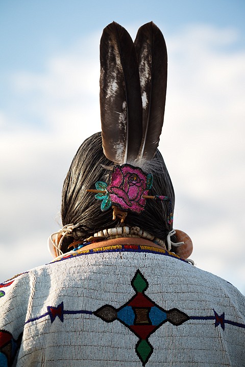 &lt;p&gt;A senior Native American woman wears feathers in her hair as
part of her regalia.&lt;/p&gt;