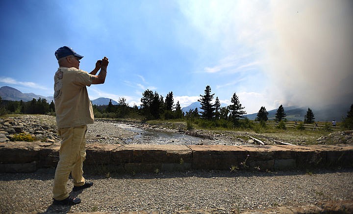 <p>Roger Anderson of Princeton, Massachusetts, takes photos of the smoke plume billowing over East Glacier on Wednesday afternoon, July 22, from St. Mary. The Reynolds Creek Fire has grown from 2,000 to 4,000 acres causing the closure of nearly half of Going-to-the-Sun Road and creating a smoke plume that has spread beyond the borders of the park into Canada. Going-to-the-Sun Road is the only road goes up and through Glacier National Park. It crosses the continental divide at Logan Pass and is currently closed from Big Bend, which is before visitors reach Logan Pass, all the way to St. Mary. (Brenda Ahearn/Daily Inter Lake)</p>