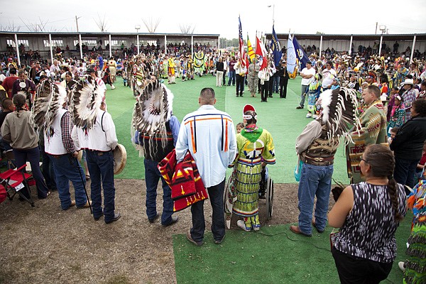<p>Performers and onlookers look on during the grand entrance at the North American Indian Days celebration on July 14. The ceremony was delayed half because of rain.</p>
