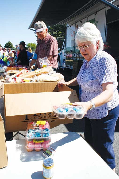 Joyce Luiten, Moses Lake, unpacks a box of cupcakes during the 2nd Harvest food distribution Wednesday at McCosh Park.