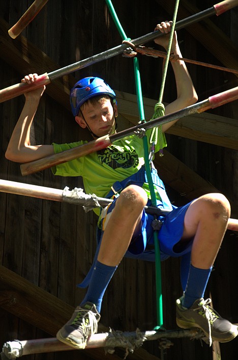 <p>Richard Scott climbs a rock wall tower at Lutherhaven Camp.</p>