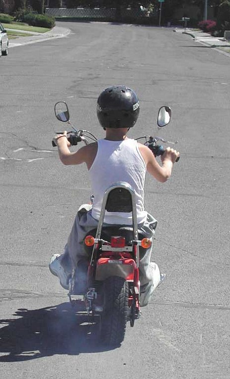 CUTLINE: Brent Meeks rides his motor bike around the street in front of his house. Lack of clarity regarding these vehicles' use and licensing have rendered the boy's purchase useless, as he has been stopped by police and warned not to use it on city streets and sidewalks.