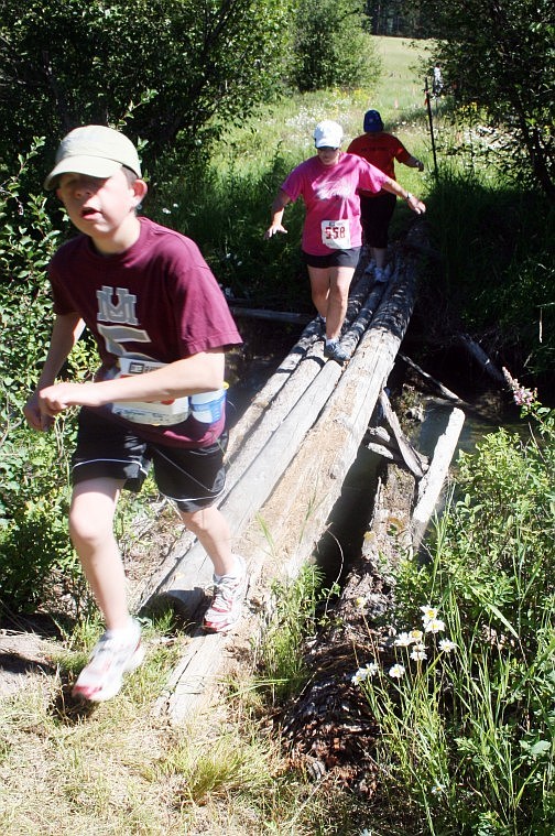 Riley Montgomery finishes running across a creek crossing followed by his mother, Denise.