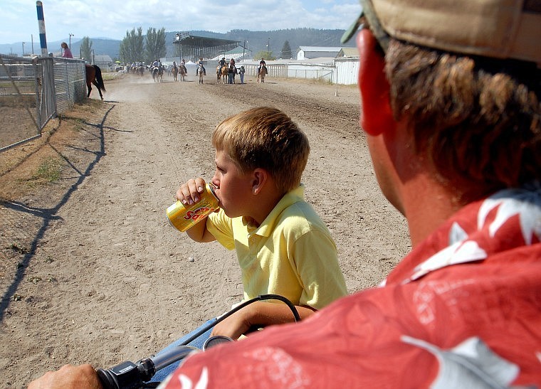 Connor rides on the front of a four wheeler while his dad Shawn drives it back towards the arena.