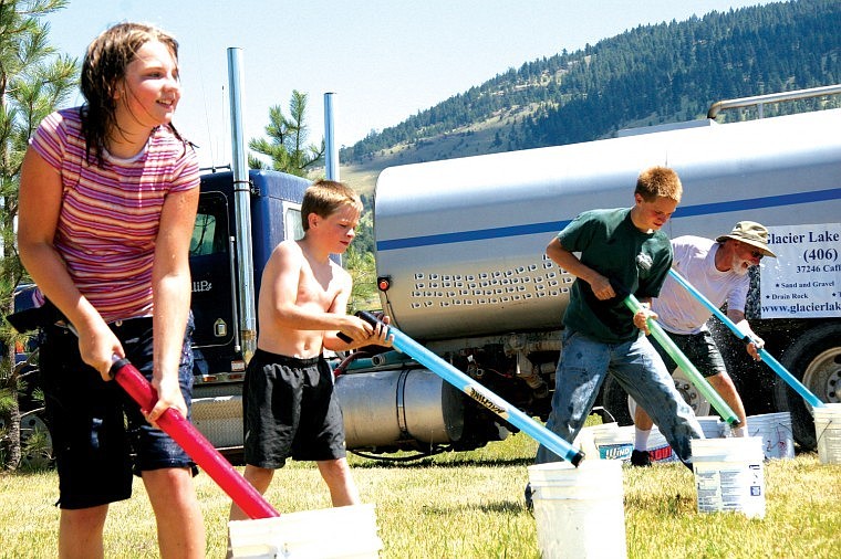 Veleena O'Donnell and Kenton Sisler, 8, along with Paul Maurer, prepare to do battle during &quot;Water Wars&quot; in Big Arm on Saturday. The event was part of a 100-year celebration of the town, and a fundraiser for the old one room school house.