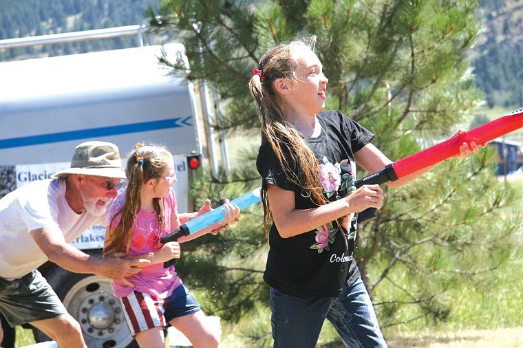 Hope Bruner splashes away while her sister Faith gets a hand from Paul Maurer in soaking the opponent during &quot;Water Wars&quot; in Big Arm last Saturday.