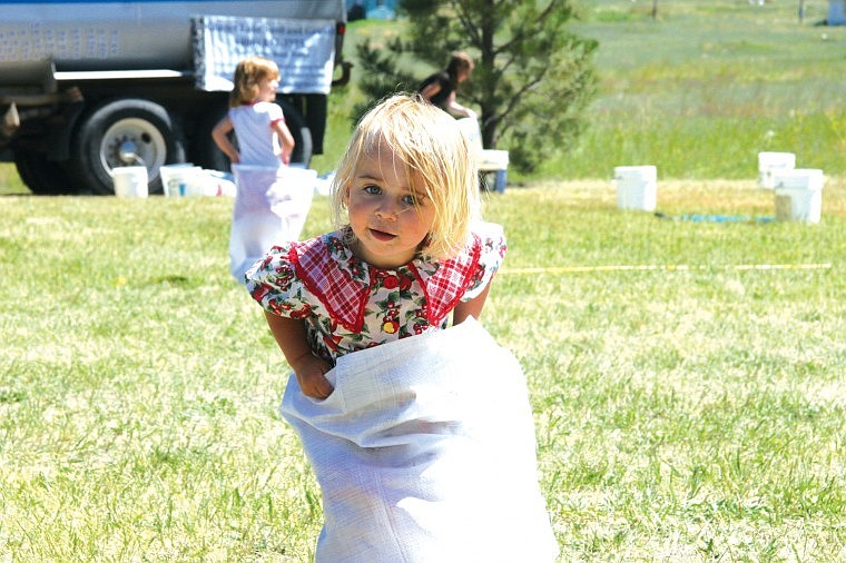 Two-year-old Mylie Hargesheimer hops along during the sack race at Saturday's 100-year celebration in Big Arm.