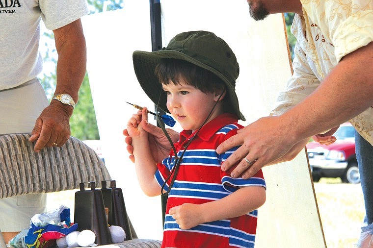 Three-year-old Danny James takes aim at some balloons while playing darts at Saturday's 100-year celebration in Big Arm.