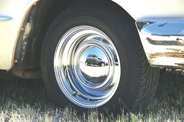 A 1930 Ford Model A is reflected in the hubcap of a 1963 Chevy Impala during Saturday's 100-year celebration in Big Arm.