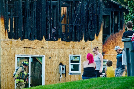 &lt;p&gt;Neighborhood families watch as firefighters and police officers walk around a house on East Nettleton Gulch Road where a fire erupted Sunday night.&lt;/p&gt;