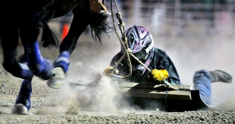 Morgan Tuttle holds on and keeps her focus while she gets dragged along the surface of the Flathead County Fairgrounds during the Devil's Cowhide event as part of O-Mok-See Nationals Thursday evening.