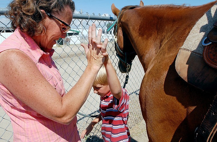 Cameron Kohr gets a high five from his mother, Tonya, on Wednesday after hearing that he took first place in the 7 and Under Division for Pole Bending at the National O-Mok-See at the Flathead County Fairgrounds in Kalispell.