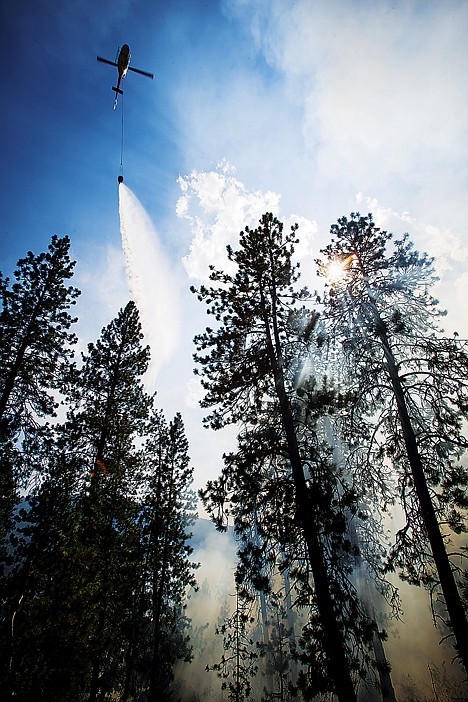 &lt;p&gt;A helicopter drops water from a bucket while aiding crews from the air.&lt;/p&gt;