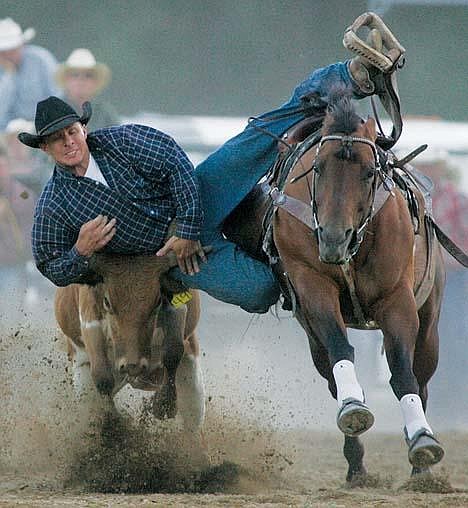 Cody Echevarria of Moscow, Idaho, launches high on the steer's head during the steer wrestling venue last