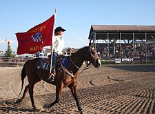 Abby Knight, of Charlo, carries the Flathead Nation flag out onto the rodeo arena grounds during Pioneer Days last weekend in Ronan.