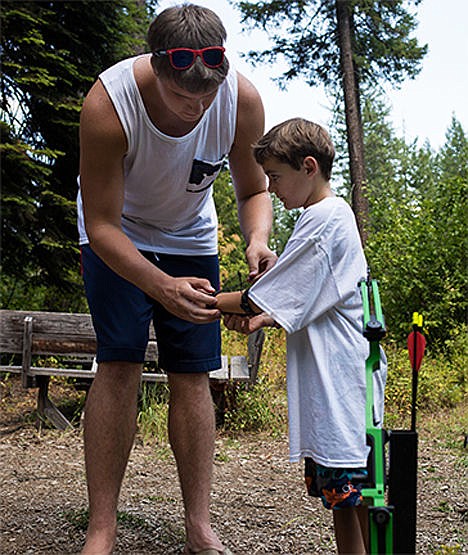 &lt;p&gt;Gonzaga University center Ryan Edwards helps Camp Goodtimes camper Elliott Attrill, 9, attach protective equipment to Attrill's arm before shooting arrows at the camp's archery range on Monday during the basketball team's visit to the camp at YMCA Camp Reed. The week-long camp is directed towards families affected by childhood cancer, and Gonzaga athletes have visited the camp every year.&lt;/p&gt;