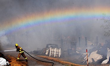 <p>A Creston firefighter sprays down a large pile of wood inside of the yard.(Aaric Bryan/Daily Inter Lake)</p>