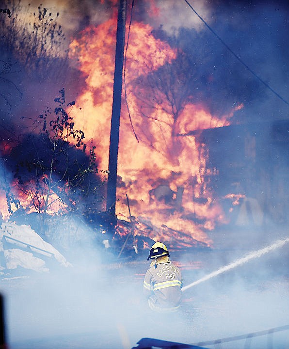 <p>A Creston firefighter battles the blaze at a structure fire/grassland fire on Mountain View Drive in Evergreen on Wednesday, August 5. (Brenda Ahearn/Daily Inter Lake)</p>