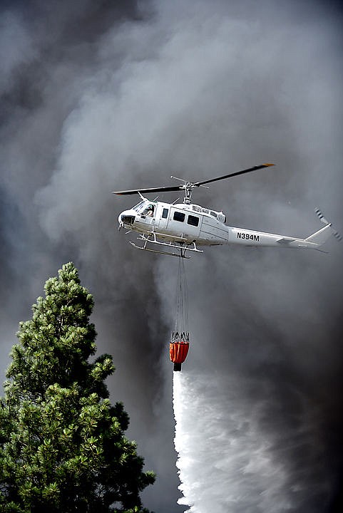 &lt;p&gt;A DNRC helicopter flies through smoke to drop water on the scene of a massive fire on Mountain View Drive in Evergreen on Wednesday, August 5. Evergreen Fire and Rescue were joined by the Kalispell and Creston fire departments, the Flathead County Sheriff's Office, forest firefighters and other first responders. (Brenda Ahearn/Daily Inter Lake)&lt;/p&gt;