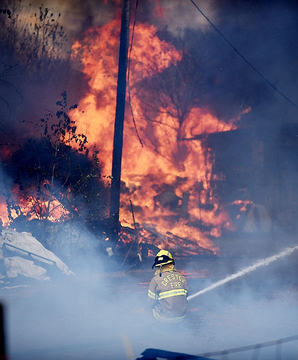 <p>A Creston firefighter battles the blaze at a structure fire/grassland fire on Mountain View Drive in Evergreen on Wednesday, August 5. (Brenda Ahearn/Daily Inter Lake)</p>