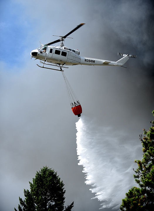 <p>A DNRC helicopter flies through smoke to drop water on the scene of a massive fire on Mountain View Drive in Evergreen on Wednesday, August 5. Evergreen Fire and Rescue were joined by the Kalispell and Creston fire departments, the Flathead County Sheriff's Office, forest firefighters and other first responders. (Brenda Ahearn/Daily Inter Lake)</p>