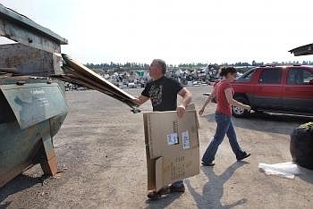 Steve Matkovich of Kalispell deposits his flattened boxes in the cardboard bin while Megan Schneiter of Kalispell grabs the rest of her recycling at the Flathead County Landfill recycling drop-off site on Monday morning. Allison Money/Daily Inter Lake