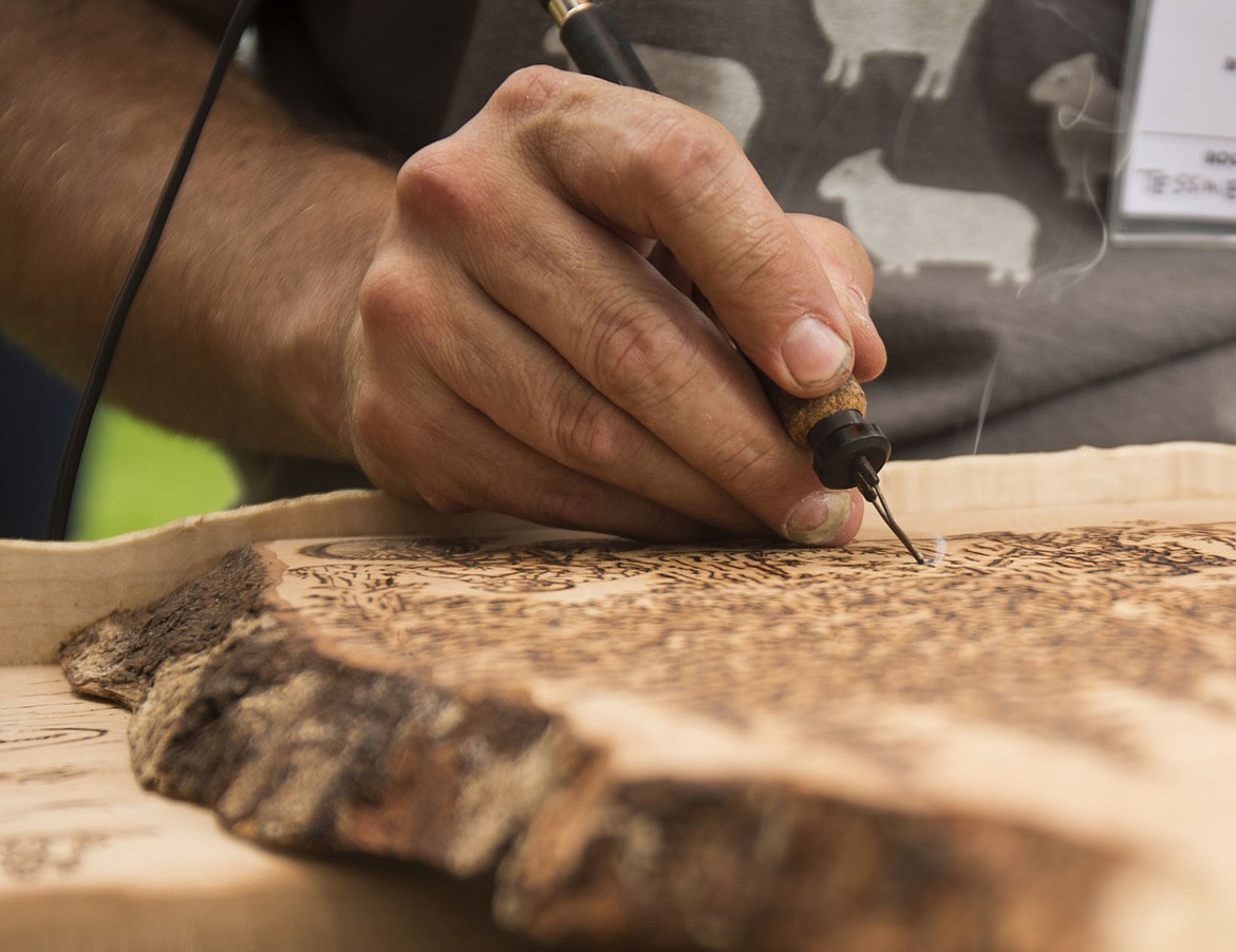 &lt;p&gt;Todd Tessmer etches various outdoor activities on a salvage piece of Curly Willow wood in the shape of the state of Idaho during Art on the Green at North Idaho College.&lt;/p&gt;