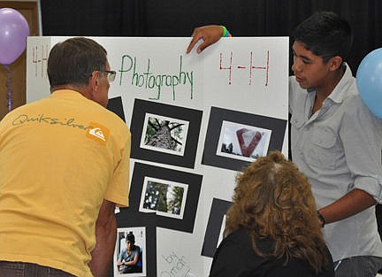 &lt;p&gt;The photography judge closely observes the photography display entered by Omar Perez.&lt;/p&gt;